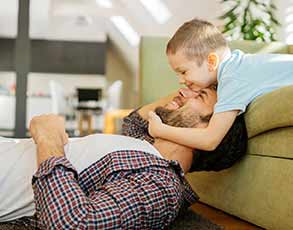 Little boy hugging his father on sofa.