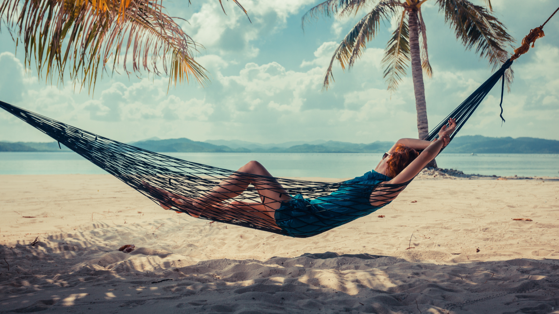 Woman relaxing on beach in hammock